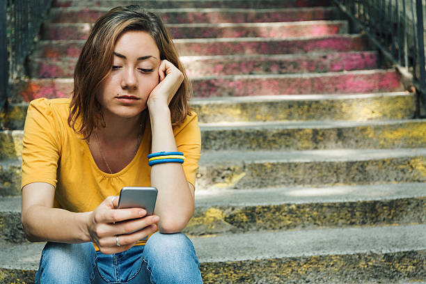 Cell phone break up Teen girl dressed in yellow t-shirt breaking up with his boyfriend through messages. Dark toning. brat stock pictures, royalty-free photos & images