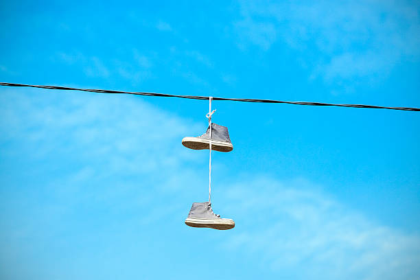 istock Old shoes hanging on an electric cable. 483934020