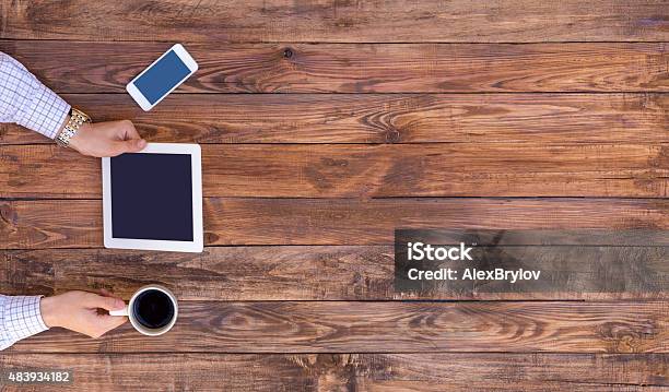 From Above Image Of Man Browsing Gadget Empty Wood Desk Stock Photo - Download Image Now