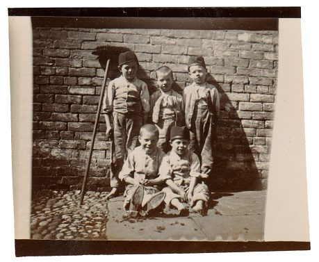 Vintage photo from the late Victorian early Edwardian period showing a group of poor children on the street.  England.
