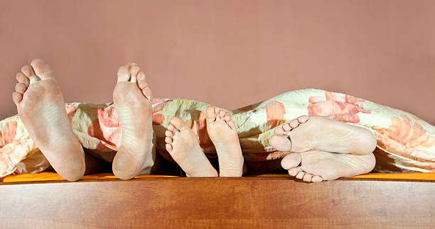 Tree pair of legs Tree pairs of legs of the happy family in bed - father, mother and child bed human foot couple two parent family stock pictures, royalty-free photos & images