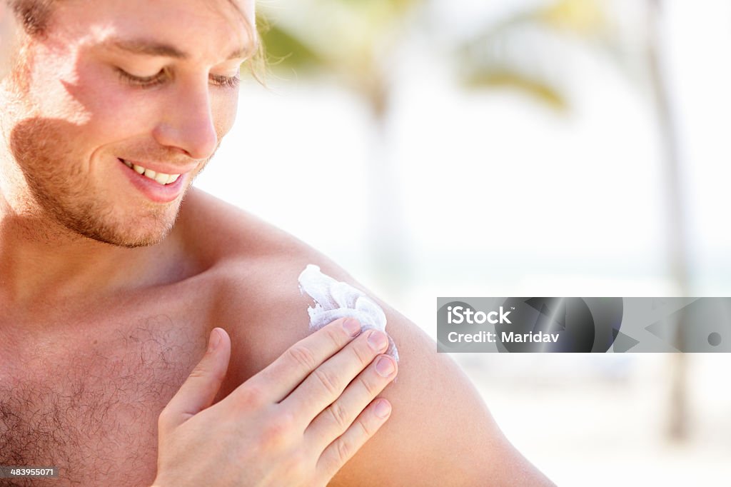 Solar cream / sunscreen Solar cream / sunscreen. Man putting sunblock sun screen cream on the beach under the sun during vacation on travel resort. Young caucasian male model. Men Stock Photo