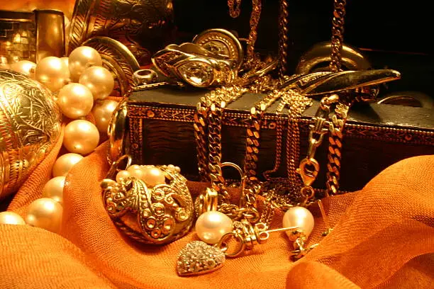 Jewelry laying over a wooden, indian jewelry box on orange chiffon.