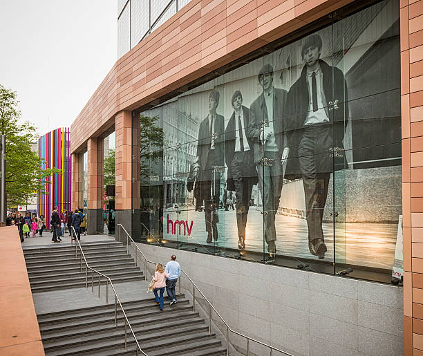 Liverpool, UK - May 18, 2013: A large format poster of The Beatles in the window of an HMV shop in central Liverpool, with people walking on the stairs below and the street.