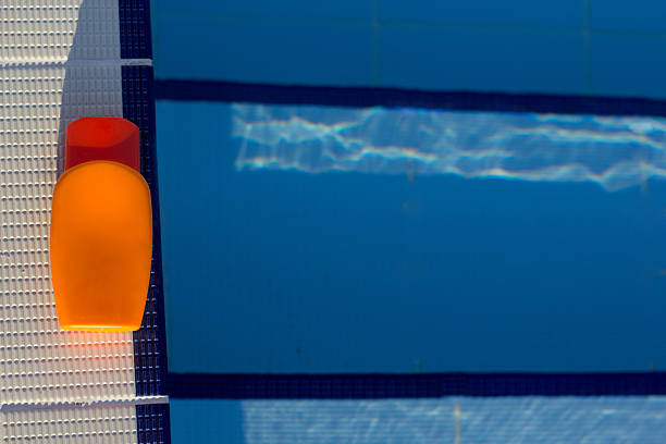 istock Orange jar with sunscreen lotion near swimming pool 483956422