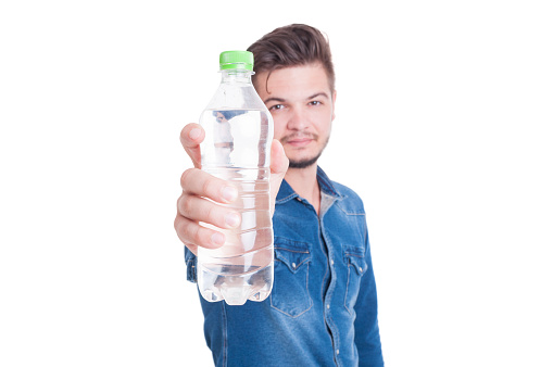 Man showing plastic bottle with cold water to the camera isolated on white studio background