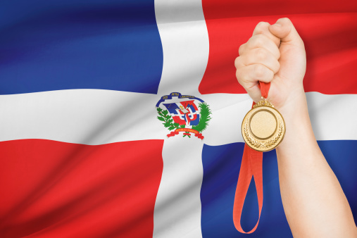 Sportsman holding gold medal with flag on background - Dominican Republic