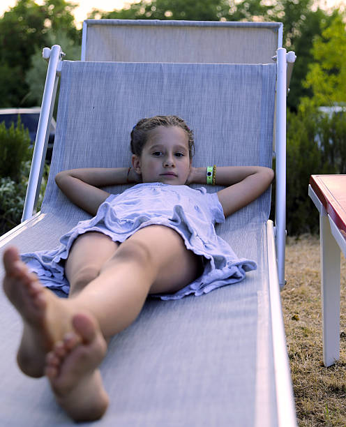 beautiful barefoot little girl rests on deck at sunset