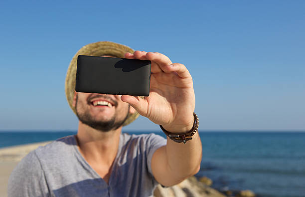 istock Smiling man taking selfie at the beach 483969296
