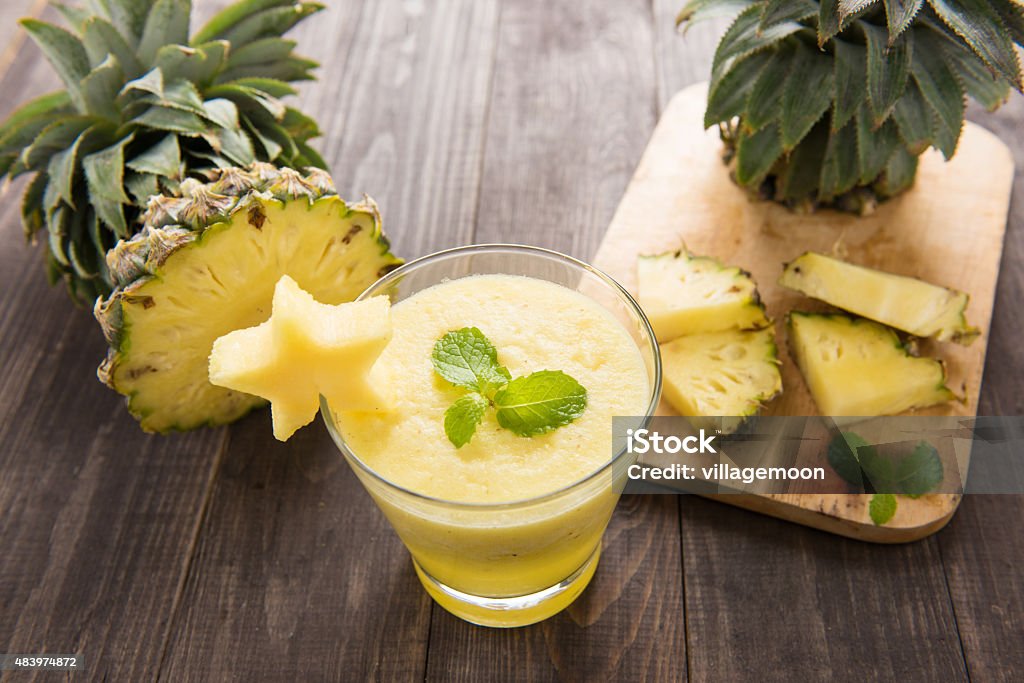 Pineapple smoothie with fresh pineapple on wooden table Pineapple smoothie with fresh pineapple on wooden table. 2015 Stock Photo