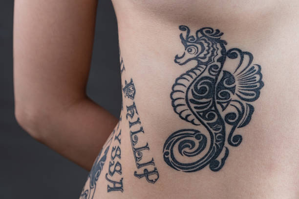 Queer tattoo artist tattooing a client