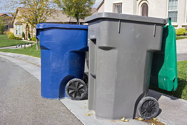 Trash Bins Ready for Pickup Couple of trash bins awaits pickup off a residential street. curb photos stock pictures, royalty-free photos & images