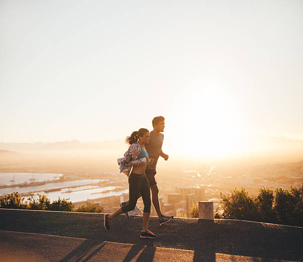 istock Young couple running together on hillside road 483979772