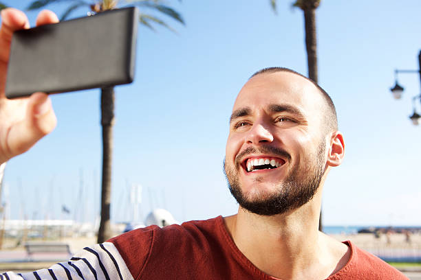 istock Young man laughing when taking a selfie with mobile phone 483980338