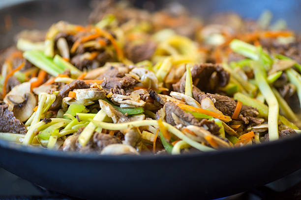 Noodles with pepper, carrot, mushrooms, zucchini and meat on wok.