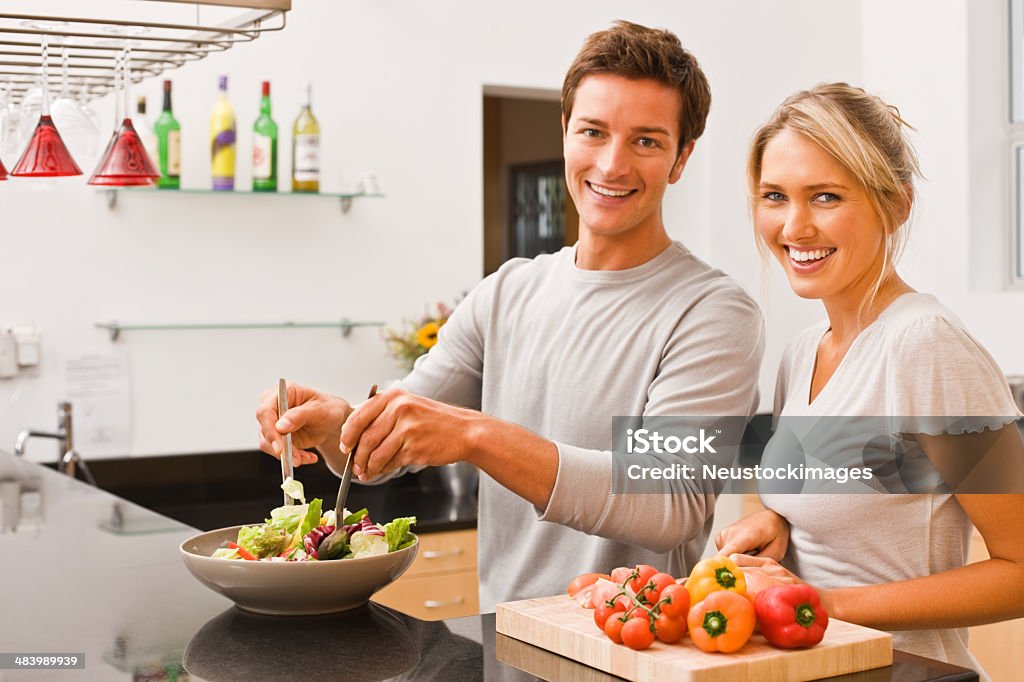 Young man tossing salad and woman cutting vegetable Portrait of young man tossing salad and woman cutting vegetable A Helping Hand Stock Photo