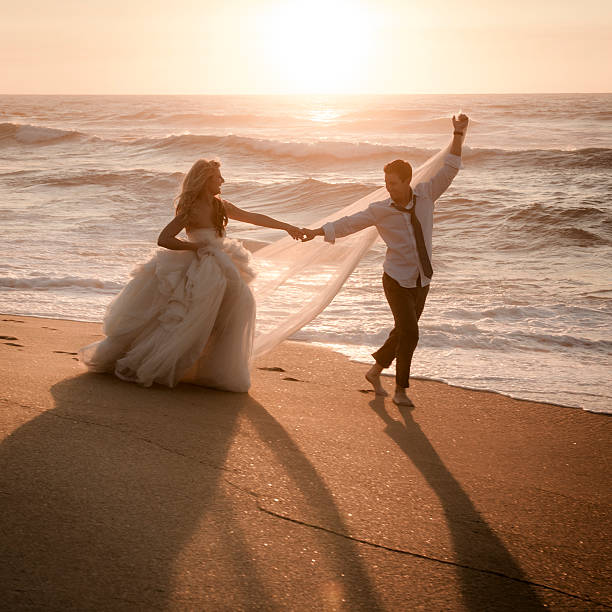 Bride and groom dancing on beach at sunrise stock photo