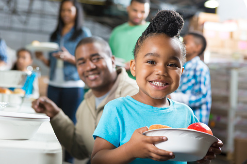 Preschool age African American child at soup kitchen with family