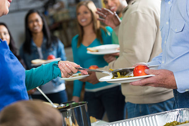 istock Volunteers serving meal to people in line at soup kitchen 483992733