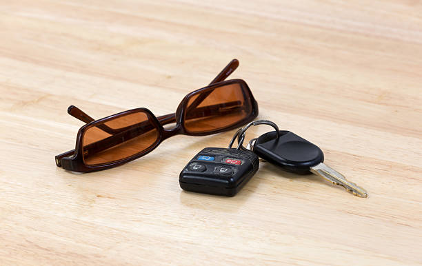 Car keys and sunglasses A set of car keys with a pair of sunglasses on a wood countertop. car keys table stock pictures, royalty-free photos & images