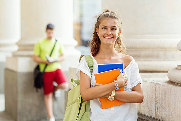 istock School girl holding textbooks and smiling 483994320