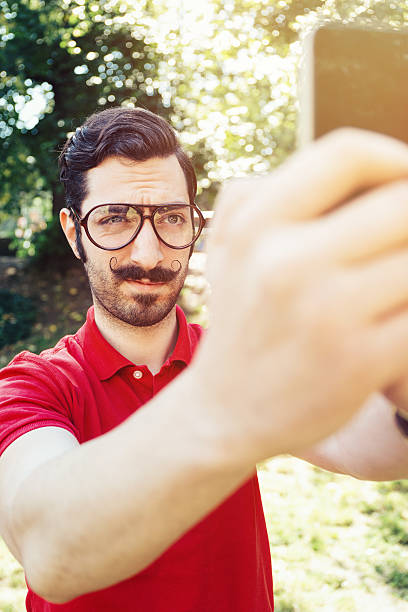 молодой человек, делая selfie in the park - risible стоковые фото и изображения