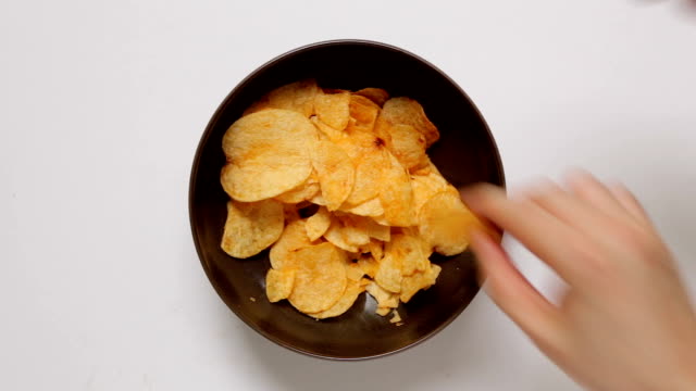 Hands Taking Potato Chips from Bowl
