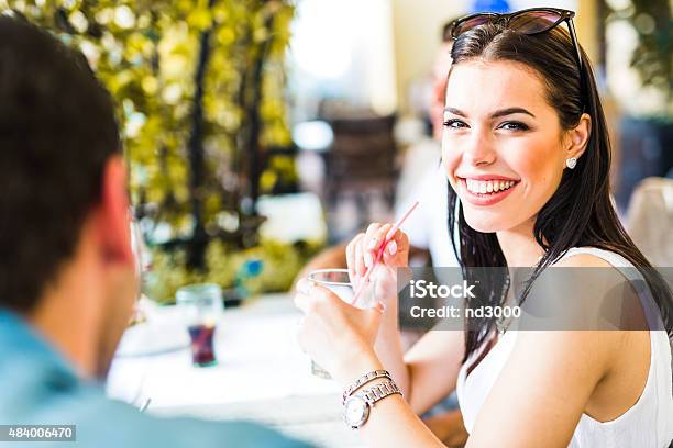 Beautiful Young Woman Sitting At A Table Outdoors And Drinking Stock Photo - Download Image Now