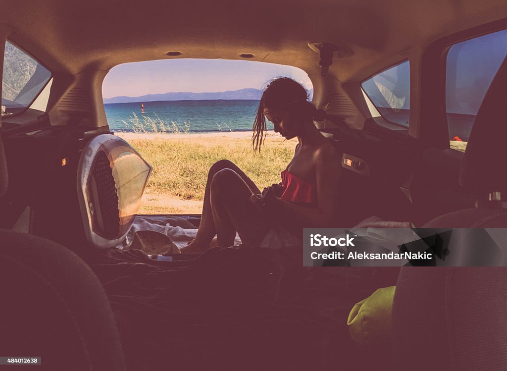Enjoying the life... Photo of young stylish woman enjoying the view at the seashore from the car trunk Lifestyles Stock Photo