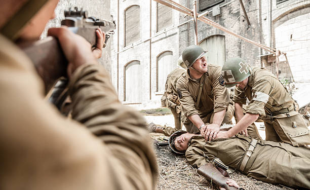 WWII Medic Administering First Aid to Wounded Soldier in Battle Vintage photograph of authentic World War II army soldier in battle reenactment. triage stock pictures, royalty-free photos & images