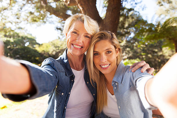 mulher idosa e filha a tirar uma selfie - wireless technology cheerful granddaughter grandmother imagens e fotografias de stock