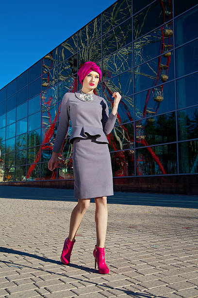 Beautiful woman in front of a building Fashion photo of a beautiful woman in front of a building with reflection of Ferris wheel at summer time purpur stock pictures, royalty-free photos & images