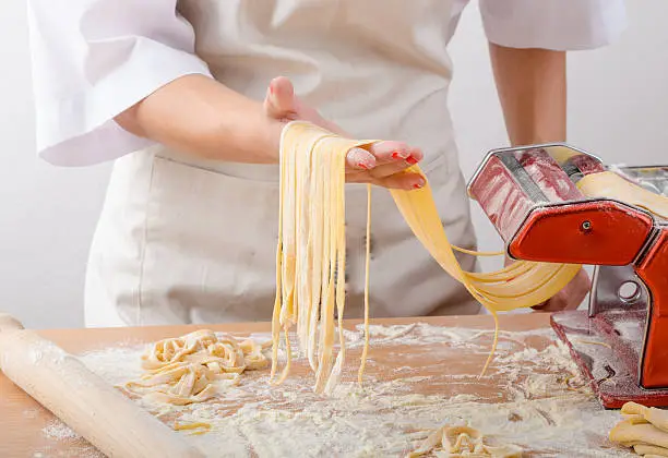 Photo of Young woman chef prepares homemade pasta