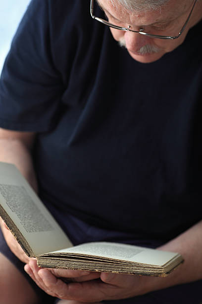 istock Older man reads a book in his lap 484023010