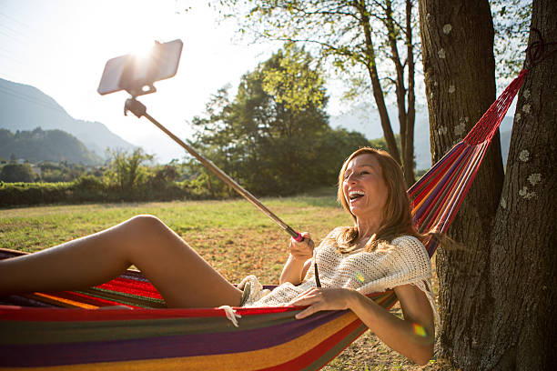 istock Woman on hammock taking selfie using phone on selfie stick 484028980