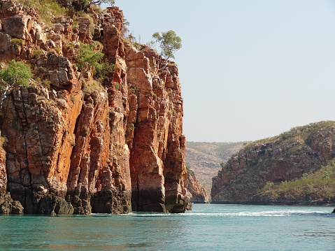 Rugged cliffs border tidal race with swiftly flowing water between islets known as horizontal waterfall feature, Kimberley, Western Australia.
