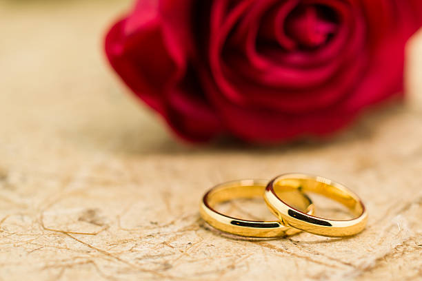 istock Wedding rings and artificial rose on brown background 484029304