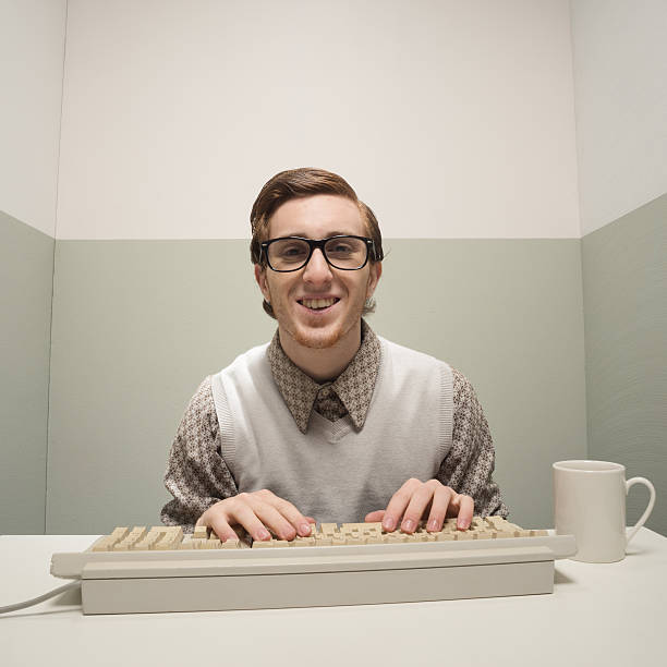 Vintage nerd on computer Vintage nerd guy working on old computer in a small room. nerd stock pictures, royalty-free photos & images