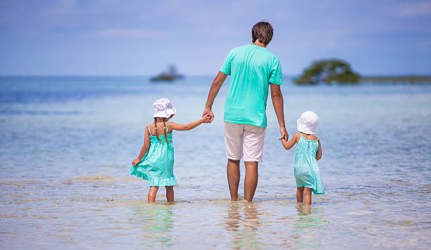 istock Back view of young father and two little kids walking 484037437