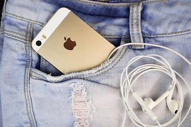 Apple iPhone 5s Gold in a blue denim pocket Kiev, Ukraine - August 10, 2015: Apple iPhone 5s Gold in a blue denim pocket and iPhone earphones, close up leather pocket clothing hide stock pictures, royalty-free photos & images