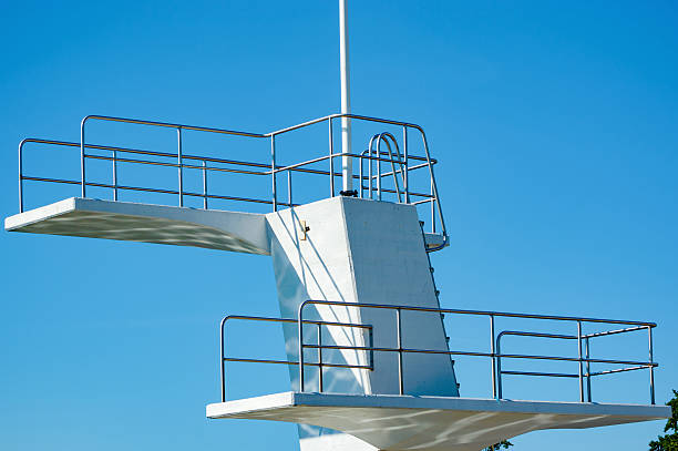 Diving board A white diving board or tower against a clear blue sky. Reflections are seen underneath. No person visible. school sport high up tall stock pictures, royalty-free photos & images