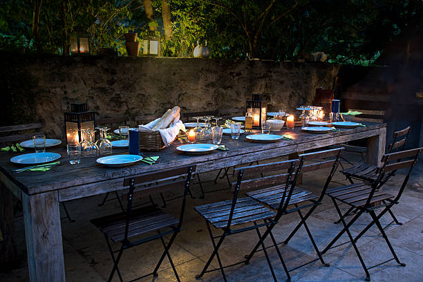 amplio ambiente rústico mesa dispuesta para una cena al aire libre en la noche - wood chair outdoors rural scene fotografías e imágenes de stock