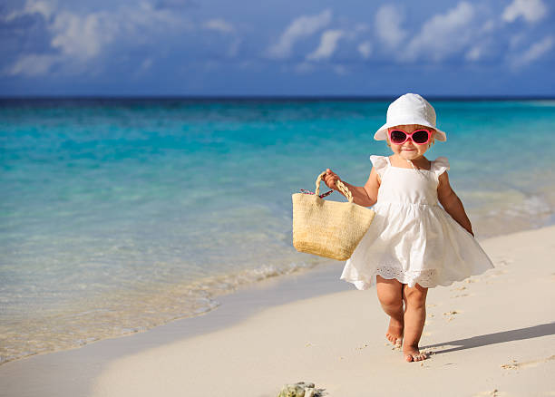 cute little girl walking on summer tropical beach stock photo