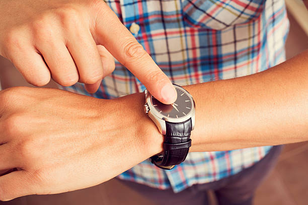 istock young man tapping his finger on his wristwatch 484049756