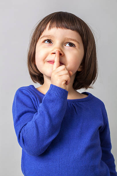 istock dreamy cute young girl playing with her finger on lips 484055540