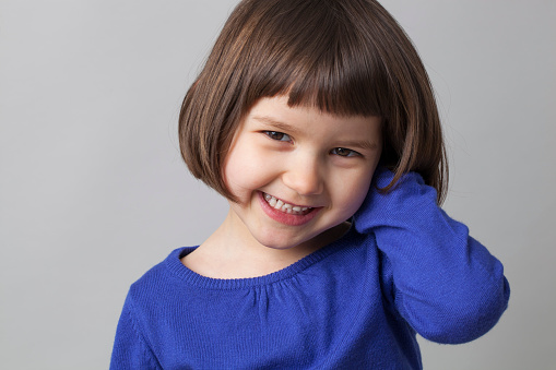 portrait of young happy preschool girl smiling in front of the camera for happiness
