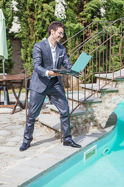 istock Angry Businessman with Computer next to Swimming Pool 484064755