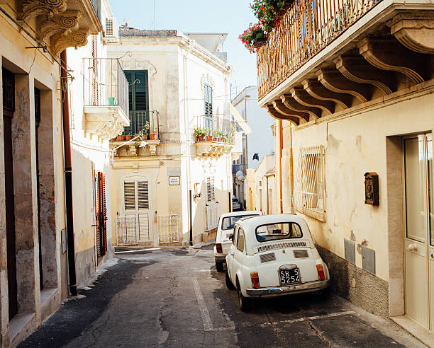 Alley with old car 500, Italy Noto, Italy -July 28, 2015: alley in Noto with two vintage cars, fiat 500 and fiat 600, Sicily, Italy. noto sicily stock pictures, royalty-free photos & images