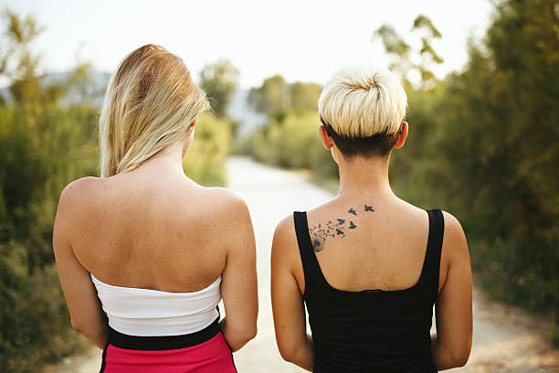 vista trasera de dos jóvenes amigos mirando vías - tattoo women back rear view fotografías e imágenes de stock