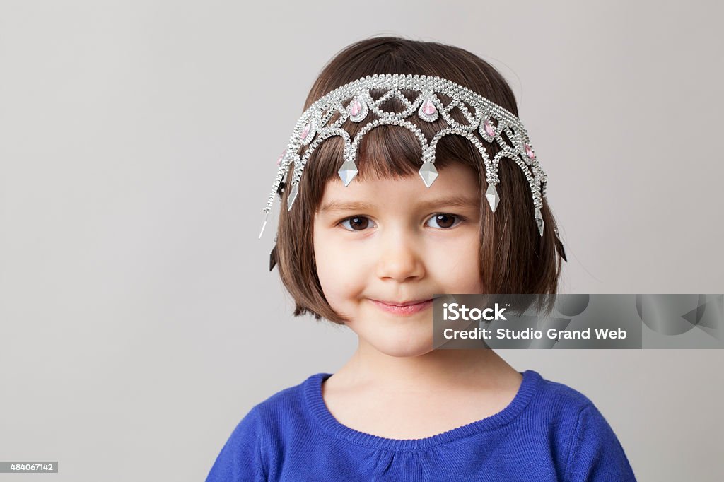 smiling preschool child with tiara for fun beauty awards concept of spoilt child with crown of queen or princess upside down on playful young smiling girl's head as sweet mollycoddled infant Baby - Human Age Stock Photo